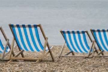 deckchairs on a pebble beach with sea in background