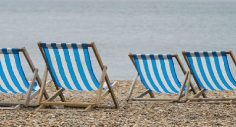 deckchairs on a pebble beach with sea in background