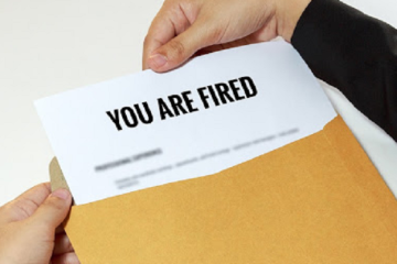 hands opening an envelope with sheet of paper declaring You are fired at top
