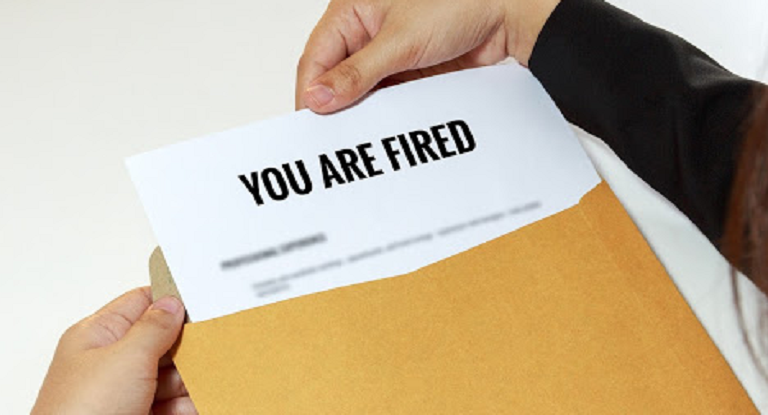hands opening an envelope with sheet of paper declaring You are fired at top