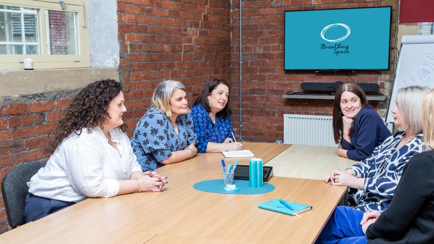 Six women sitting at conference table talking