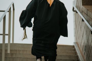 graduate in gown walking up steps