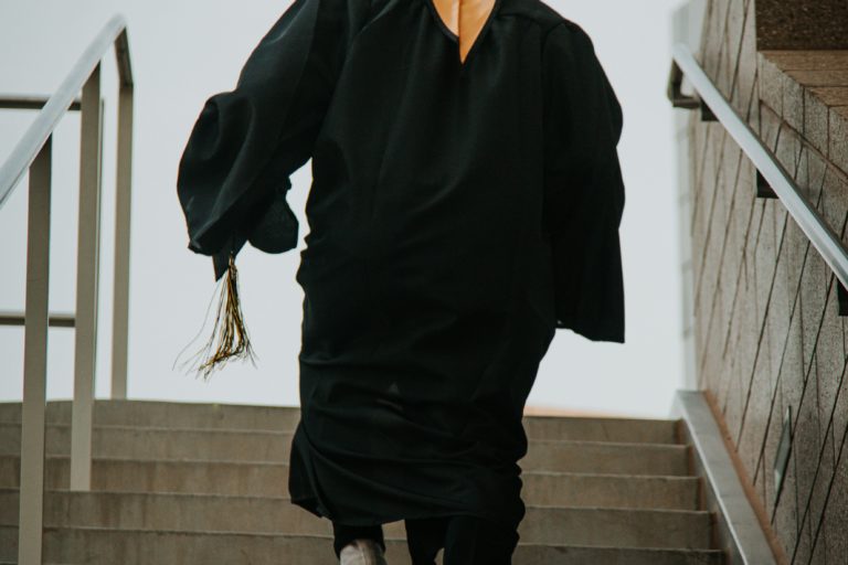 graduate in gown walking up steps
